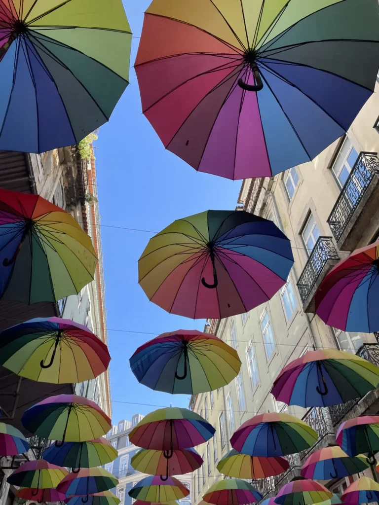 Street view in Lisbon Portugal with colorful umbrellas hanging above traditional buildings